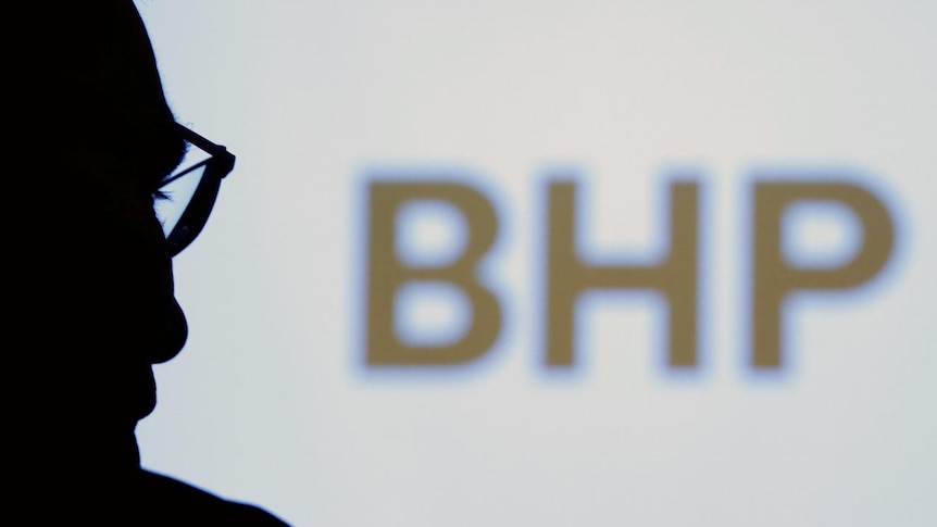 BHP chief executive Andrew Mackenzie silhouetted with logo in the background