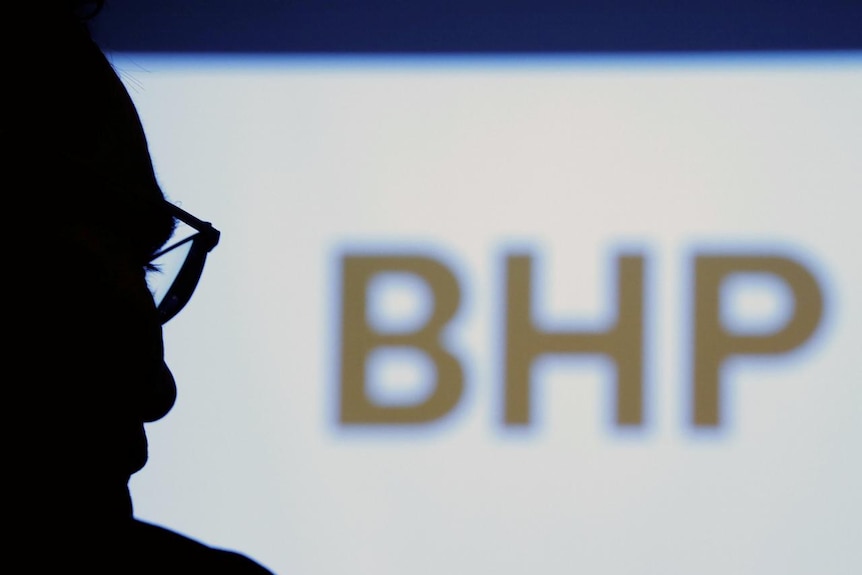 BHP chief executive Andrew Mackenzie silhouetted with logo in the background