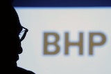 BHP chief executive Andrew Mackenzie silhouetted with logo in the background