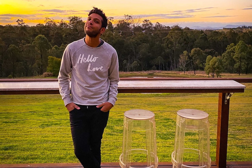 A man standing outside with the sunset in the background.