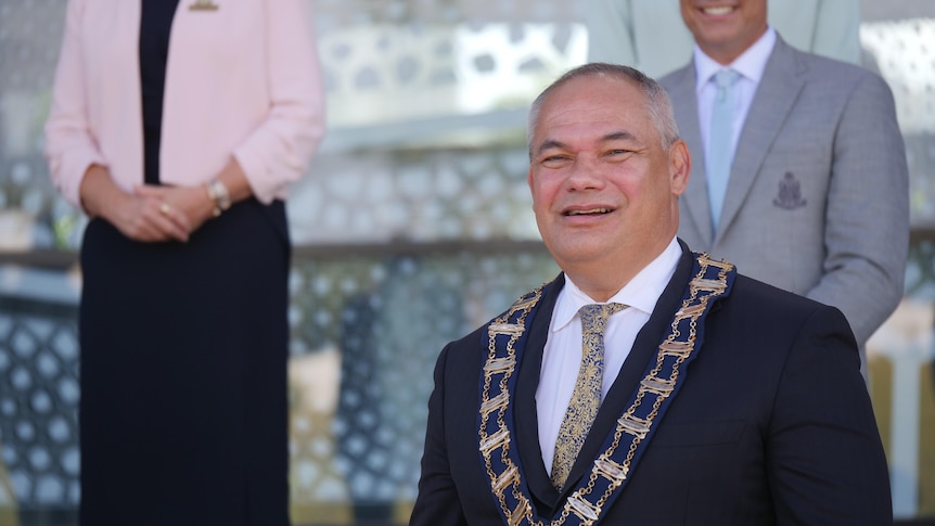 A smiling, balding man a dark suit – Gold Coast Mayor Tom Tate – wearing a ceremonial medallion.
