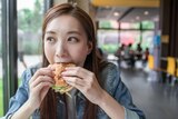 A woman smiles while eating a hamburger.