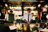 bartenders working behind a dimly-lit, upscale bar