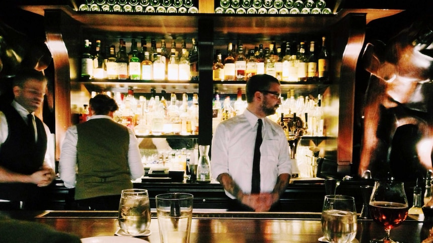 bartenders working behind a dimly-lit, upscale bar