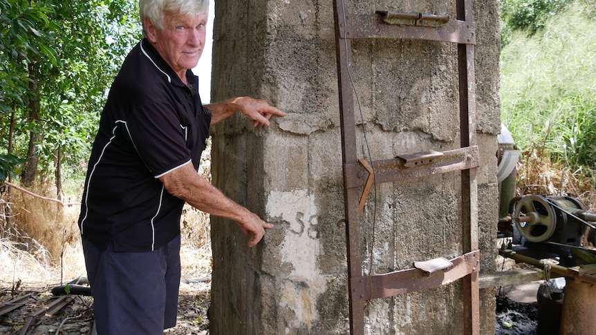 A man points out flood levels on a cement marker