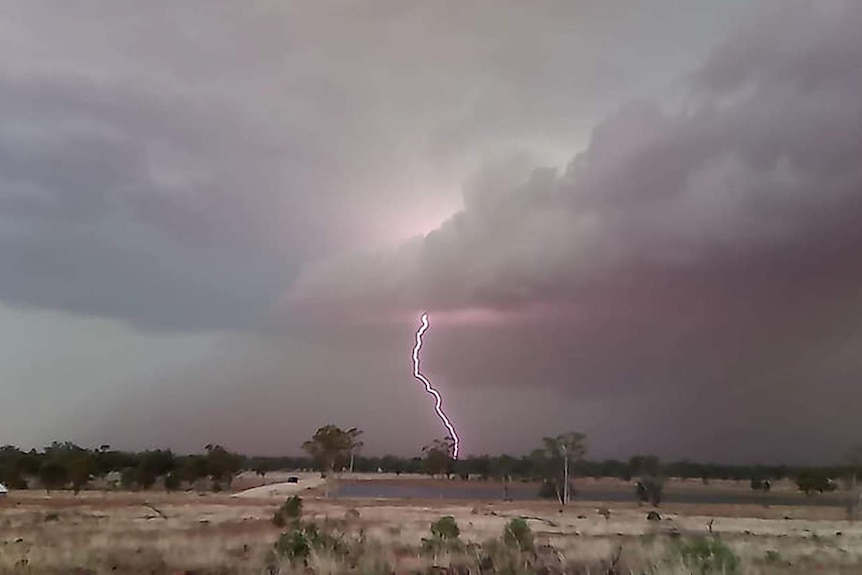 Lightning strikes the ground from grey storm clouds