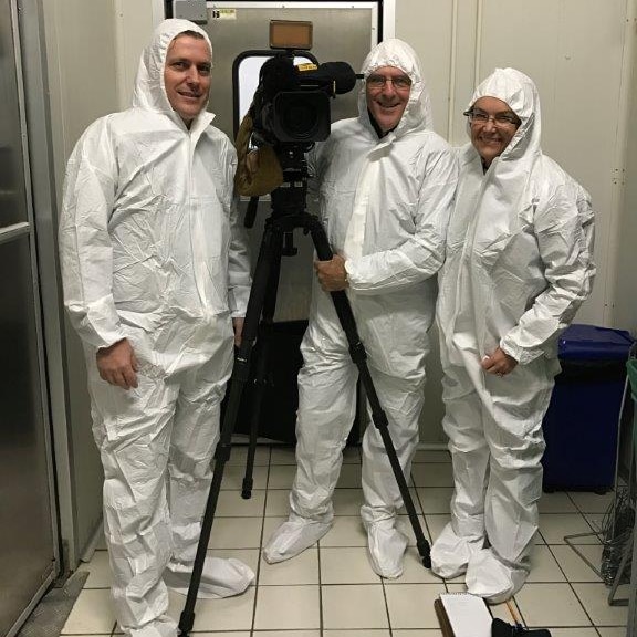 Pip Courtney and crew in head to toe white suits standing with camera.