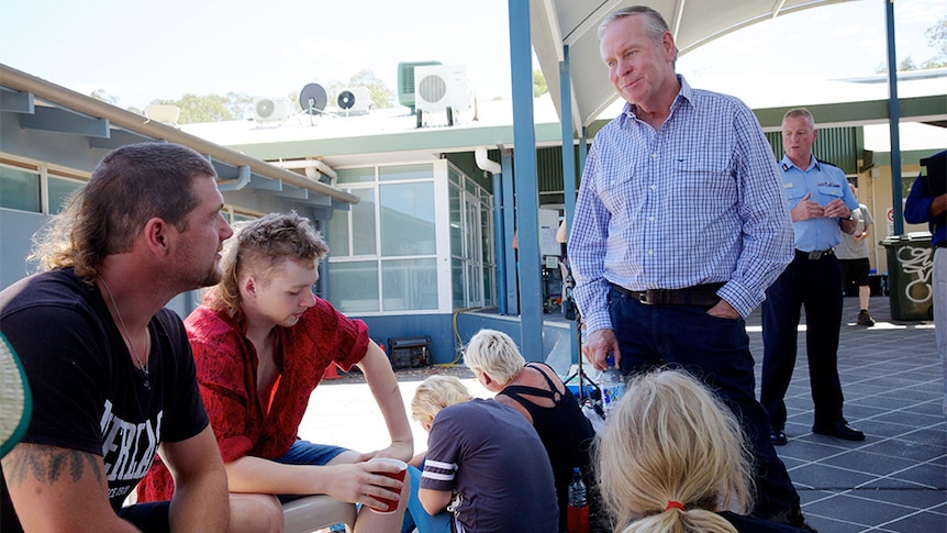Colin Barnett talks to people who are sitting down outdoors.