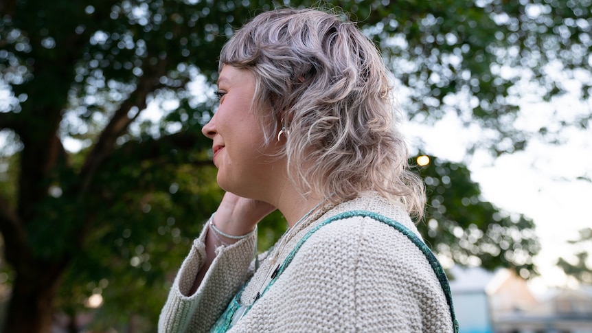 A side shot of a young woman with a blonde mullet. 