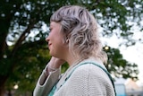 A side shot of a young woman with a blonde mullet. 