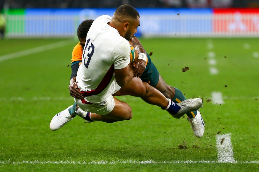 An England male rugby union player is tackled by an Australian opponent.