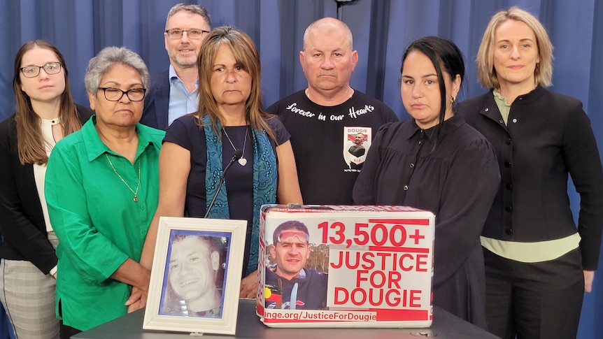 Family of Ricky “Dougie” Hampson Jr standing in front of picture and petition of Dougie 