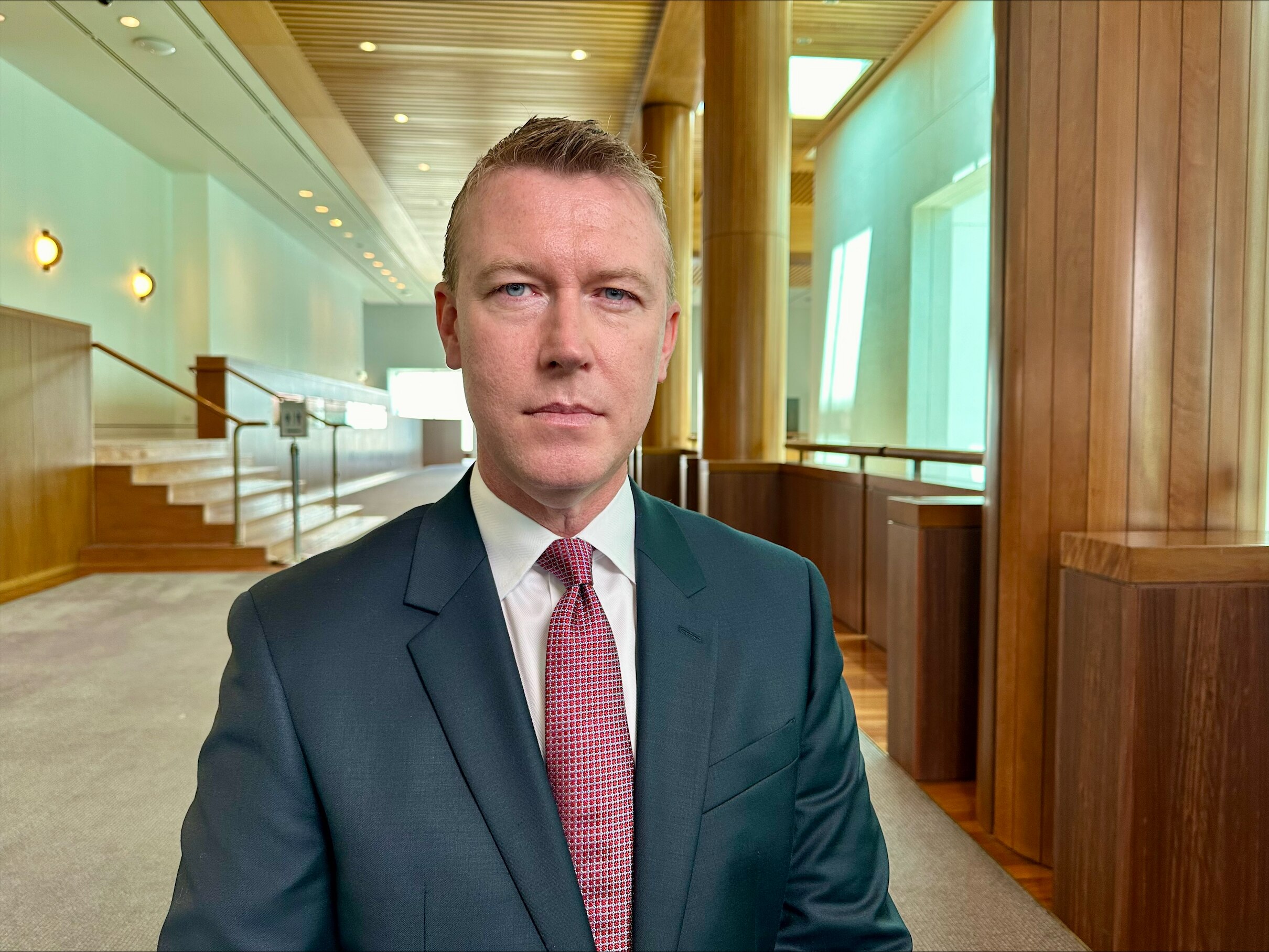 Man wearing a suit with a maroon tie.
