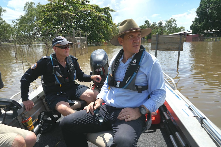 Michael Gunner on board a motor boat with a member of the NTPES driving through flooded streets.