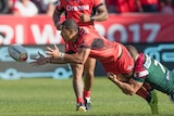 William Hopoate of Tonga offloads a pass under the tackle of Robbie Farah.