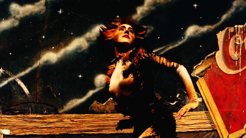 Linda Hartley performing as Demeter in Cats looks up in front of backdrop of a night sky and moon.