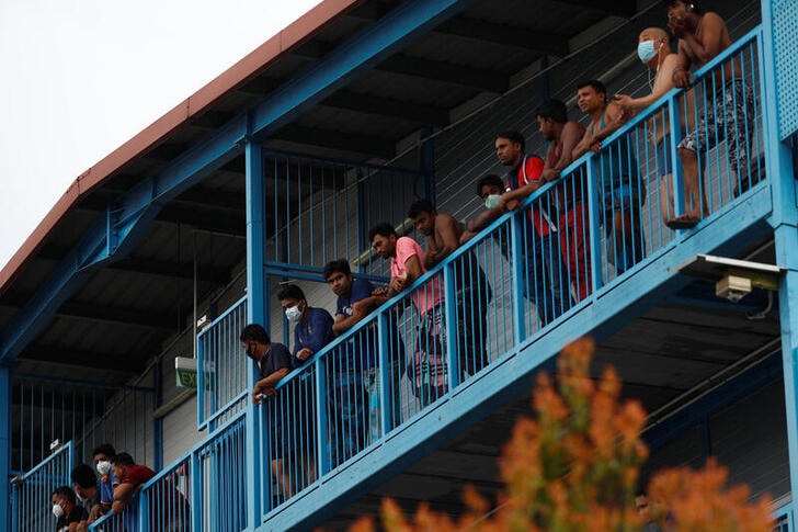 A group of men leaning against a bright blue balcony in Singapore