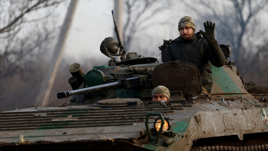 A Ukrainian serviceman waves from a tank, as Russia's attack on Ukraine continues.