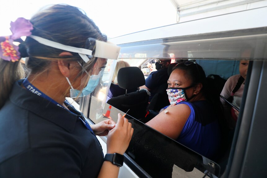A woman receives a COVID-19 vaccine through a car window