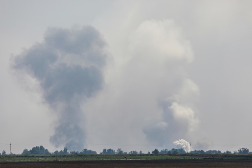 Large plumes of smoke are seen on the horizon.