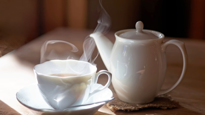 A steamy hot cup of tea next to a teapot