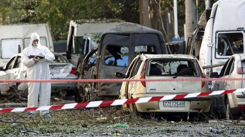 A police forensics officer examines the scene of a car bomb explosion outside the Athens stock excha