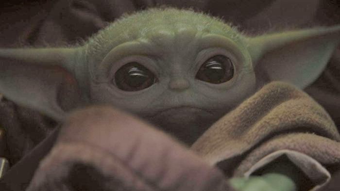 Close up of baby yoda, a green alien with pointy ears and big eyes