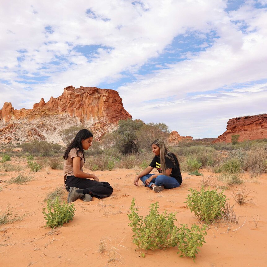 Two Aboriginal woman sitting on the ground at Rainbow Valley.