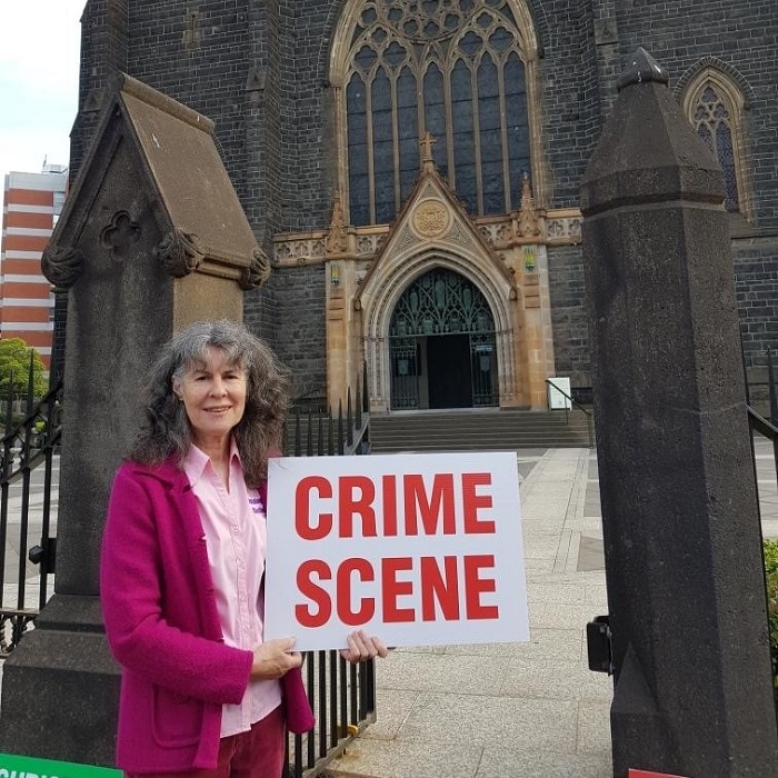 Chrissie Foster outside St Patrick's Cathedral holding a sign saying 'Crime Scene'.