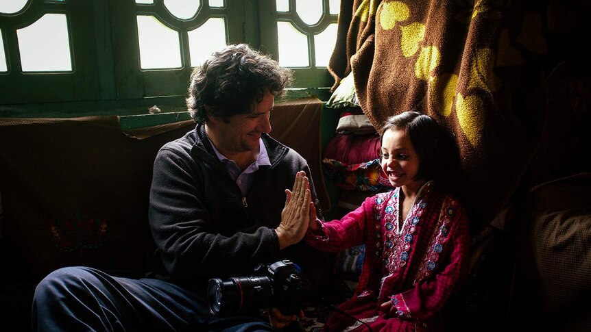 Photographer Andrea Francolini high-fives young Pakistani girl in her home.
