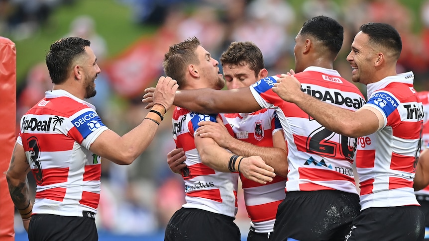 A group of NRL players celebrate after a score.