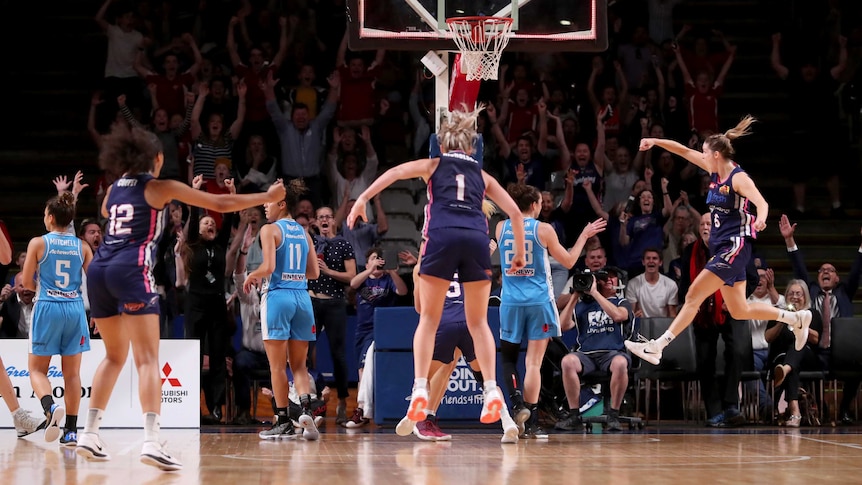 Players jump for joy after a last-second winning basket in the WNBL finals series.