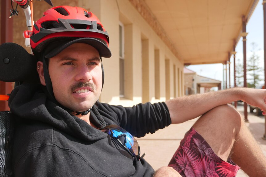 A man sitting in his trike stares off onto a regional road.