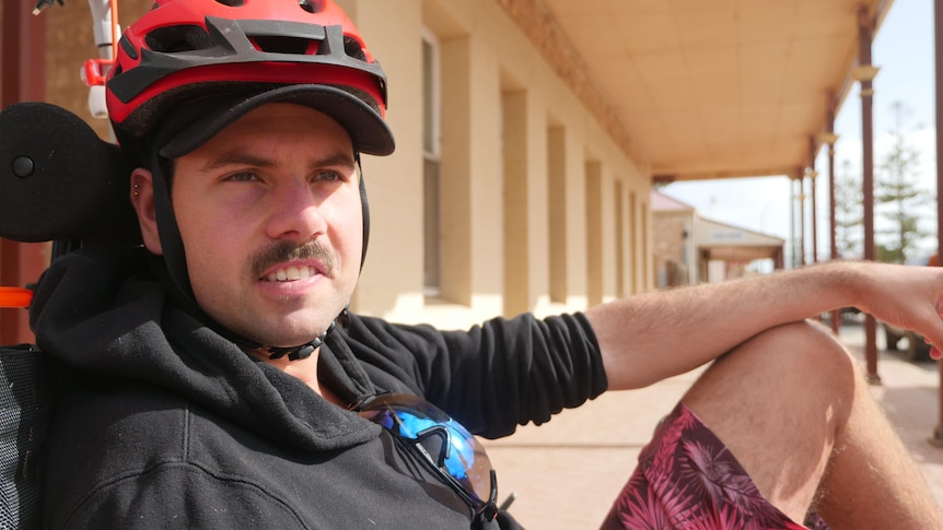 A man sitting in his trike stares off onto a regional road.