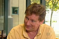 Man speaking on television with a yellow tshirt