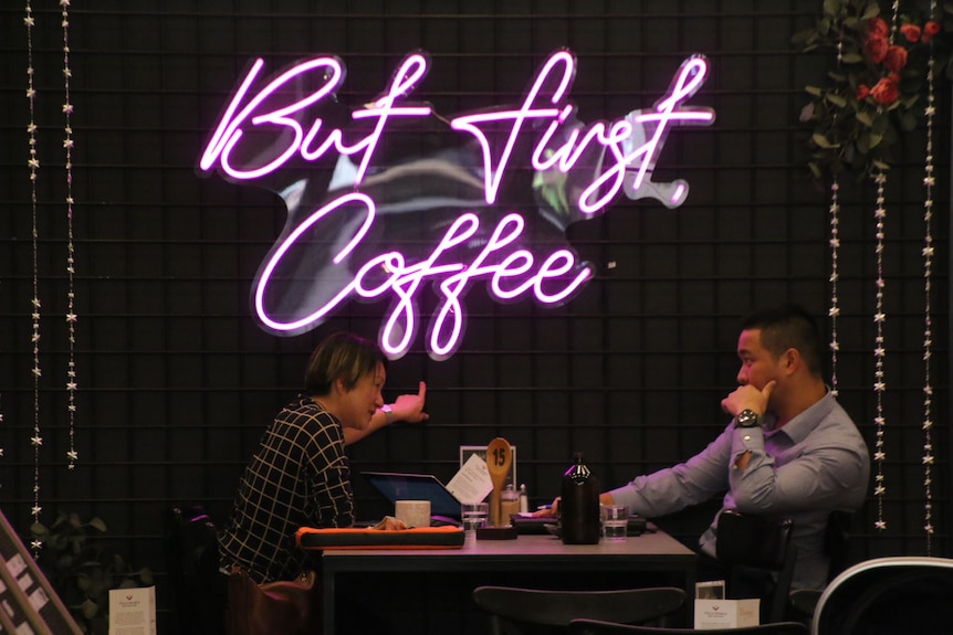 Bespoke cafe sign and people drinking coffee