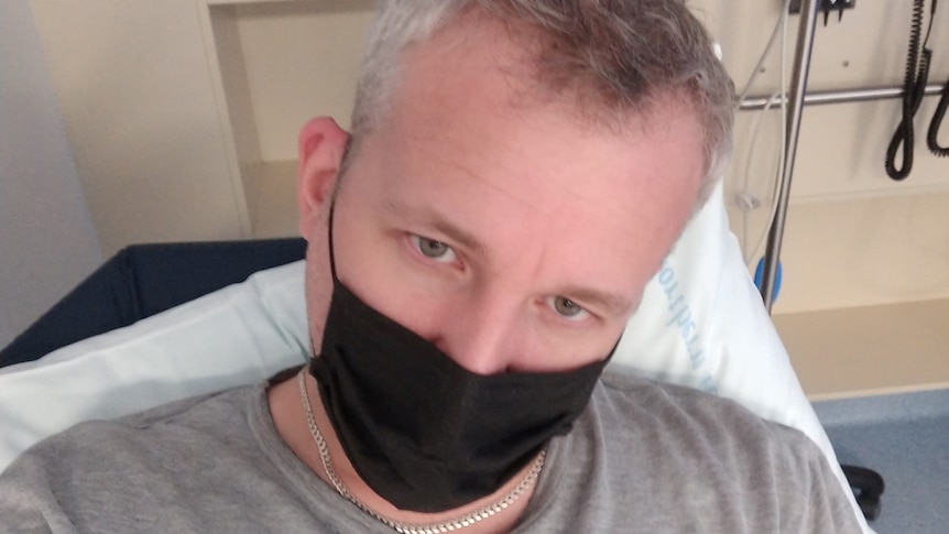 Jed Hansen wearing a black face mask takes a selfie.
