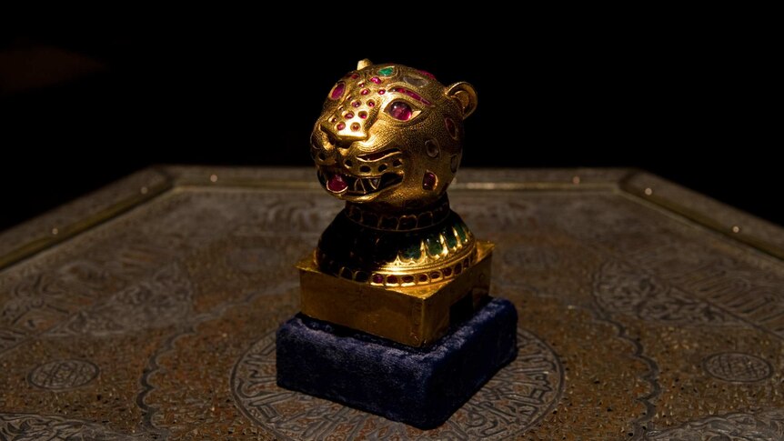A small god tiger face. Its eyes, stripes and other details are purple and green gems.