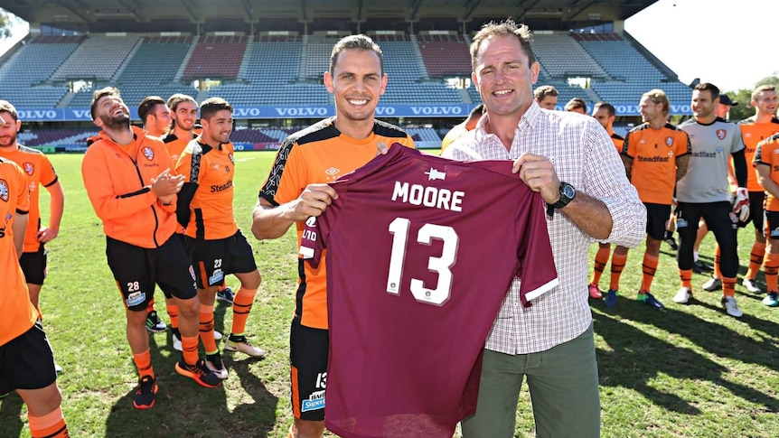 Brisbane Roar captain Jade North holds Maroon jumper alongside Billy Moore
