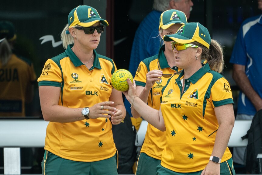 Natasha Van Eldik speaks with two other teammates while on the green.