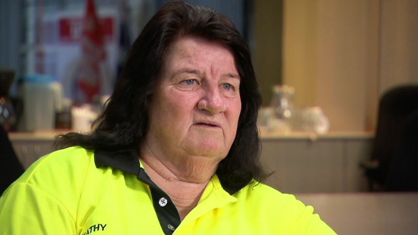 A close-up of woman with shoulder-length black hair and yellow high-vis working shirt