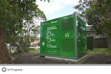 A large green box which is a community battery sitting on grass