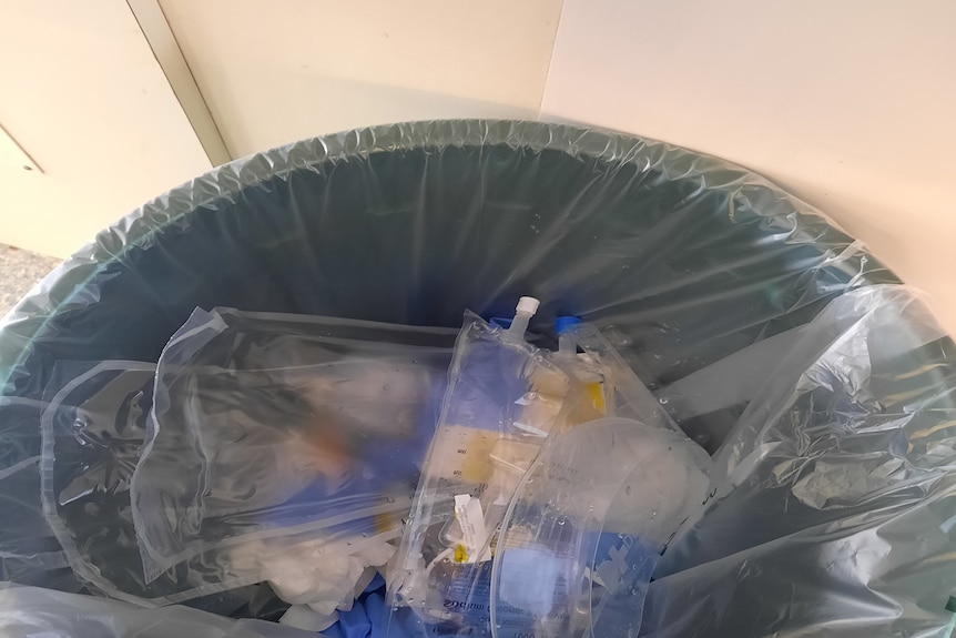 a plastic bin with iv drips and plastic gowns in it