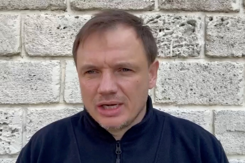 Close up of brown-haired man speaking to camera.