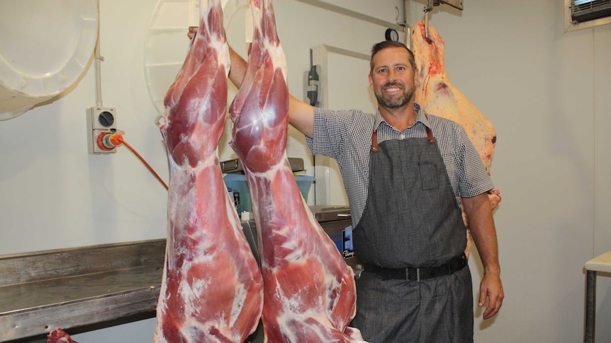 The Naked Butcher owner Gary Hine is standing beside two fresh alpaca carcasses