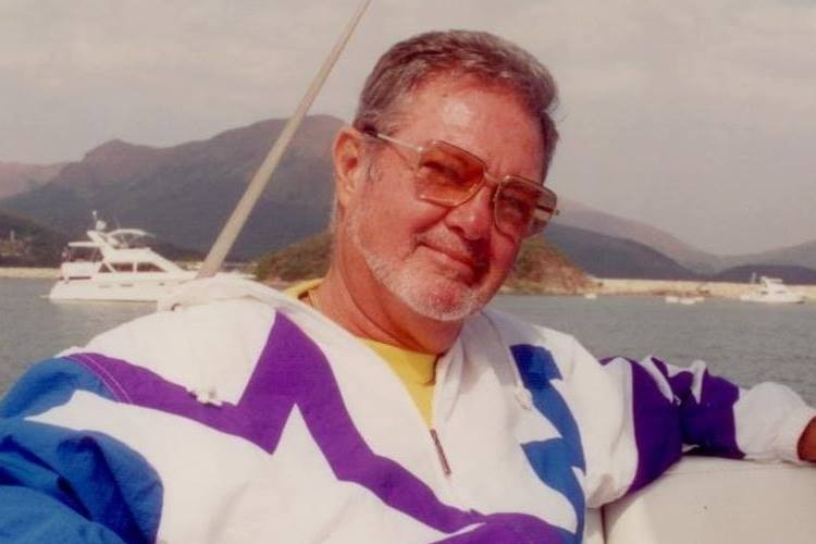 A vintage-looking photo of a man wearing sunglasses in a retro windcheater on a boat 