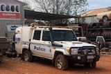 A police vehicle in front of an auto shop with its tyres slashed.
