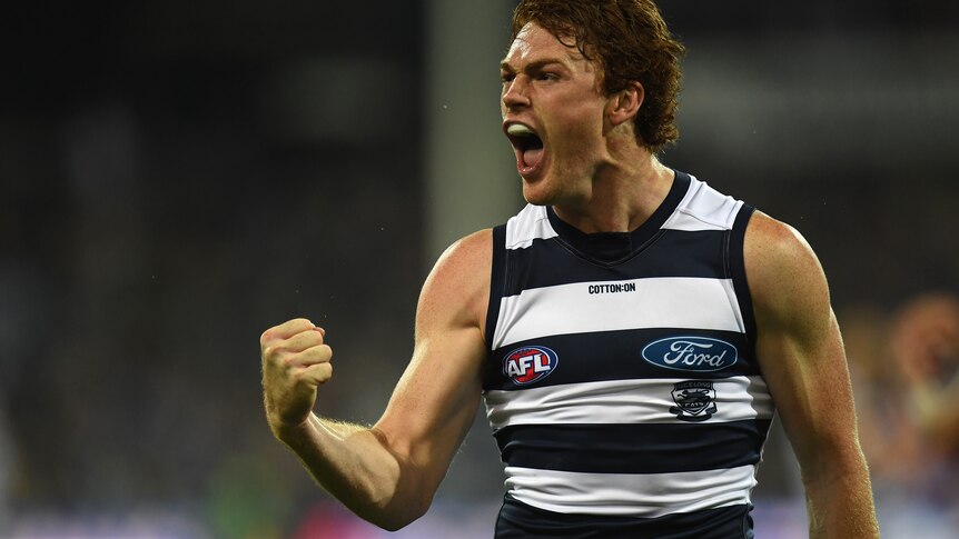 Gary Rohan pumps his fist and screams with his mouth wide open in a blue and white striped singlet