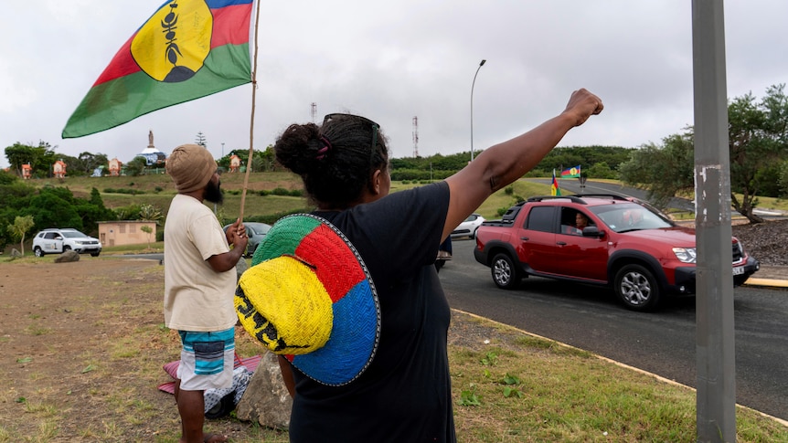A woman waves a Kanak and Socialist National Liberation Front (FLNKS) flag in Noumea