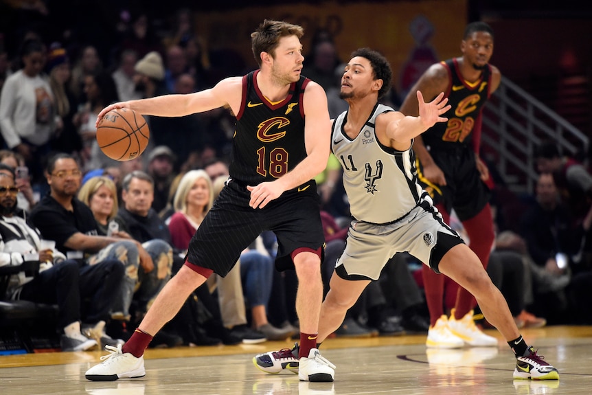 A Cleveland Cavaliers NBA player dribbles the ball while being defended by a San Antonio Spurs opponent in 2020.